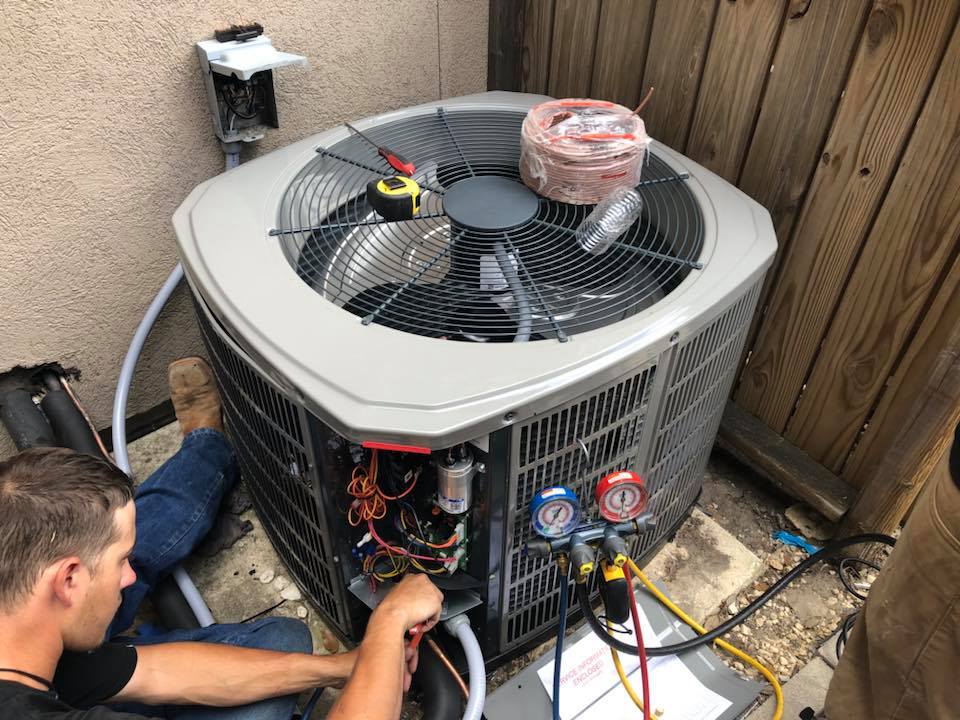 HVAC technician performing AC maintenance on an outdoor air conditioner compressor in Blanco, TX using gauges and diagnostic tools