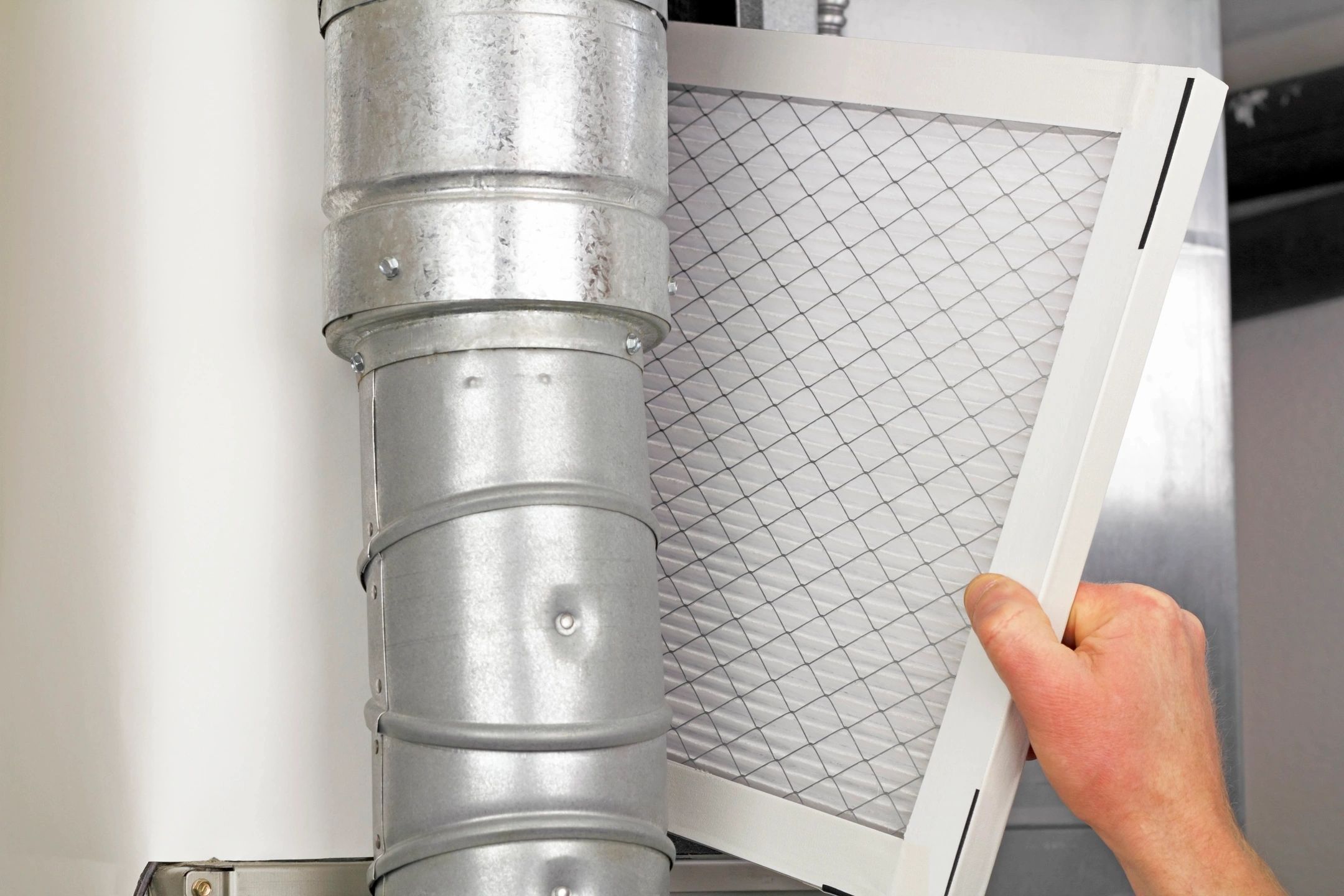 HVAC technician replacing a furnace air filter to improve indoor air quality in Blanco, TX